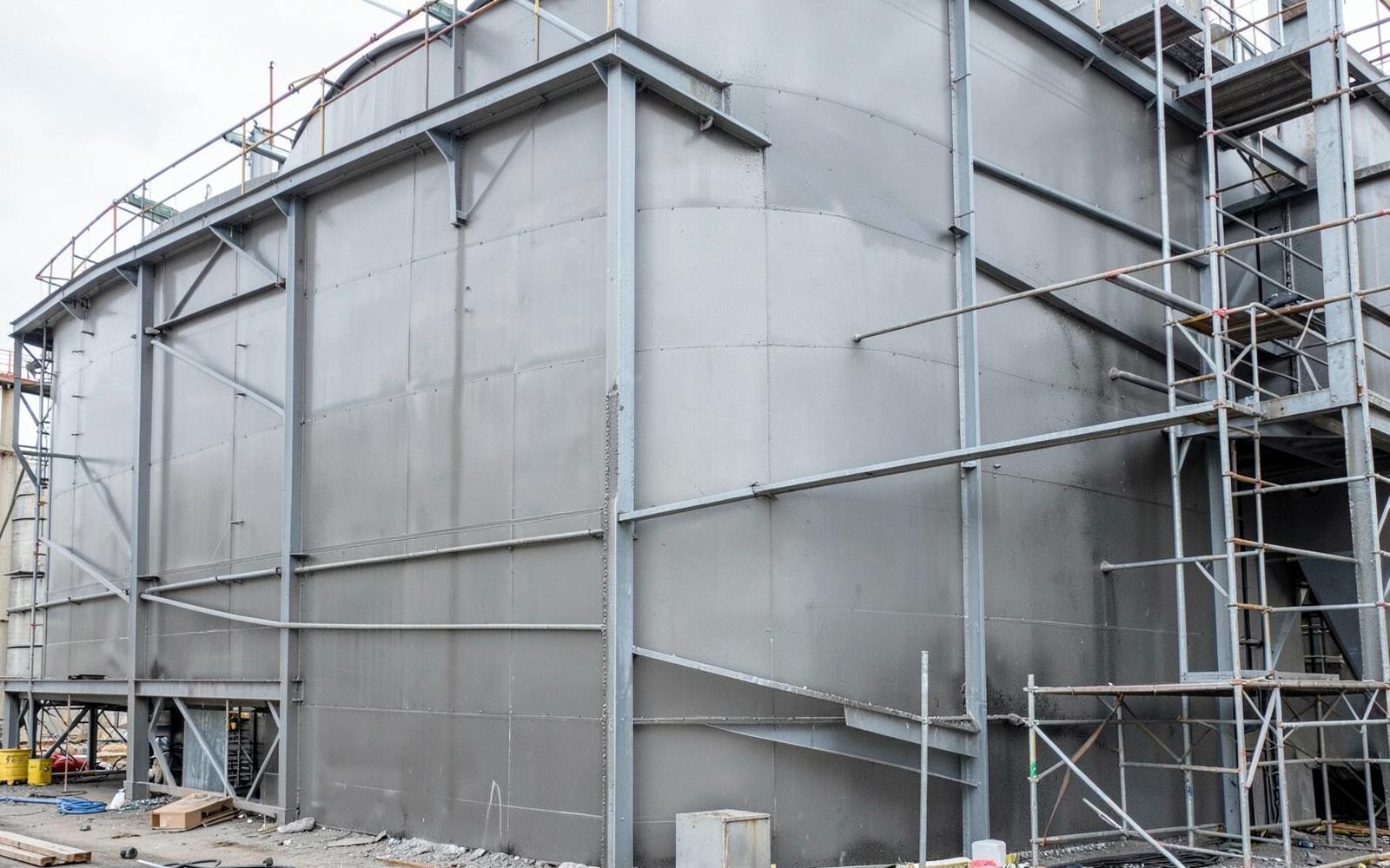 Newly coated industrial storage tank and structural steelwork with scaffolding in place. Illustrative industrial photograph.